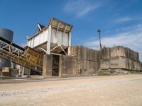 the concrete wall is a bridge over some water tanks in the desert, as well as two trucks parked on a dirt road