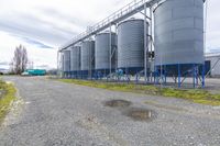 two large silos in the middle of an industrial area and the road is paved with grass