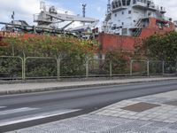 a large ship sitting behind a chain link fence on a street corner with another boat in the background