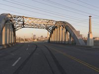 an industrial bridge crossing into the city skyline in the evening light with power lines over the road