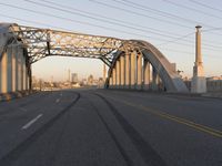 an industrial bridge crossing into the city skyline in the evening light with power lines over the road