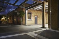 an empty dark street at night with lights on the building behind it and one side is empty