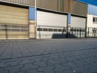 an empty street outside a commercial building with several garage doors on the side of it