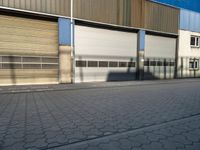 an empty street outside a commercial building with several garage doors on the side of it