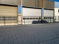 an empty street outside a commercial building with several garage doors on the side of it