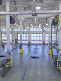 workers stand in a large industrial building with high ceilings and steel beams and pipes and a table