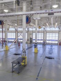 workers stand in a large industrial building with high ceilings and steel beams and pipes and a table