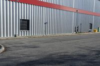 an industrial building with a red roof sits next to the street in front of the building