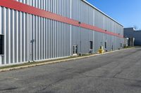 an industrial building with a red roof sits next to the street in front of the building