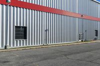 an industrial building with a red roof sits next to the street in front of the building