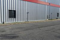 an industrial building with a red roof sits next to the street in front of the building