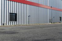 an industrial building with a red roof sits next to the street in front of the building