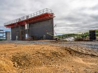 an industrial building with red scaffolding on top of it next to a pile of rubble