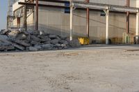 a bunch of rocks and piles of concrete in front of an industrial building on the street