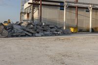 a bunch of rocks and piles of concrete in front of an industrial building on the street