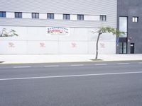 two people riding bikes on the sidewalk of an industrial building with white trim and red bricks on the side