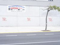 two people riding bikes on the sidewalk of an industrial building with white trim and red bricks on the side