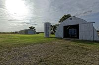 two large grain bins sit in the center of a field, surrounded by silos