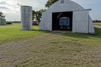two large grain bins sit in the center of a field, surrounded by silos