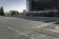 a empty parking lot with trees, buildings and sky in the background of this photograph