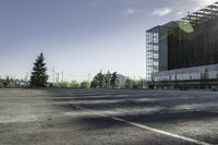 a empty parking lot with trees, buildings and sky in the background of this photograph