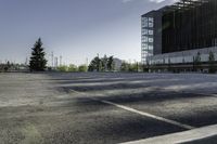 a empty parking lot with trees, buildings and sky in the background of this photograph