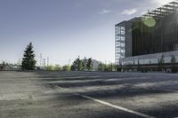 a empty parking lot with trees, buildings and sky in the background of this photograph