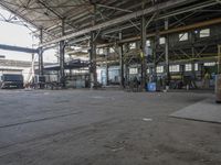 people are working in an empty industrial building with several large windows and doors that reflect the sun