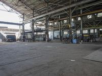 people are working in an empty industrial building with several large windows and doors that reflect the sun