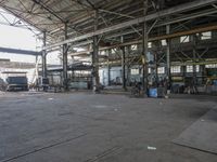 people are working in an empty industrial building with several large windows and doors that reflect the sun