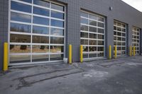 the exterior of an industrial building with yellow pole holding doors open and reflections in windows