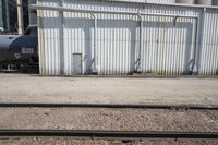 several steel containers sit next to a railroad track and buildings on a sunny day outside