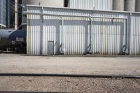 several steel containers sit next to a railroad track and buildings on a sunny day outside