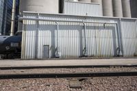 several steel containers sit next to a railroad track and buildings on a sunny day outside