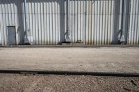 several steel containers sit next to a railroad track and buildings on a sunny day outside