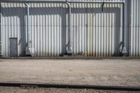 several steel containers sit next to a railroad track and buildings on a sunny day outside