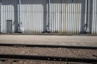 several steel containers sit next to a railroad track and buildings on a sunny day outside