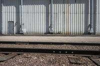 several steel containers sit next to a railroad track and buildings on a sunny day outside