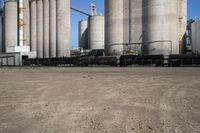 two trucks parked next to large cement silos near another building with large silos behind it