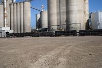 two trucks parked next to large cement silos near another building with large silos behind it