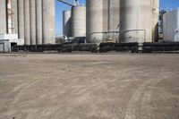 two trucks parked next to large cement silos near another building with large silos behind it