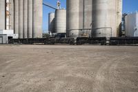 two trucks parked next to large cement silos near another building with large silos behind it