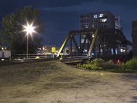 a train crossing a bridge over water next to a building at night as seen from the side