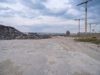 the construction site on an industrial complex with a crane and piles of rocks in the foreground