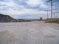 the construction site on an industrial complex with a crane and piles of rocks in the foreground