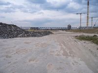 the construction site on an industrial complex with a crane and piles of rocks in the foreground