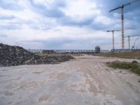 the construction site on an industrial complex with a crane and piles of rocks in the foreground