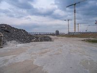 the construction site on an industrial complex with a crane and piles of rocks in the foreground