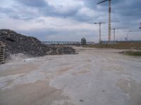 the construction site on an industrial complex with a crane and piles of rocks in the foreground