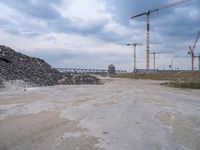 the construction site on an industrial complex with a crane and piles of rocks in the foreground